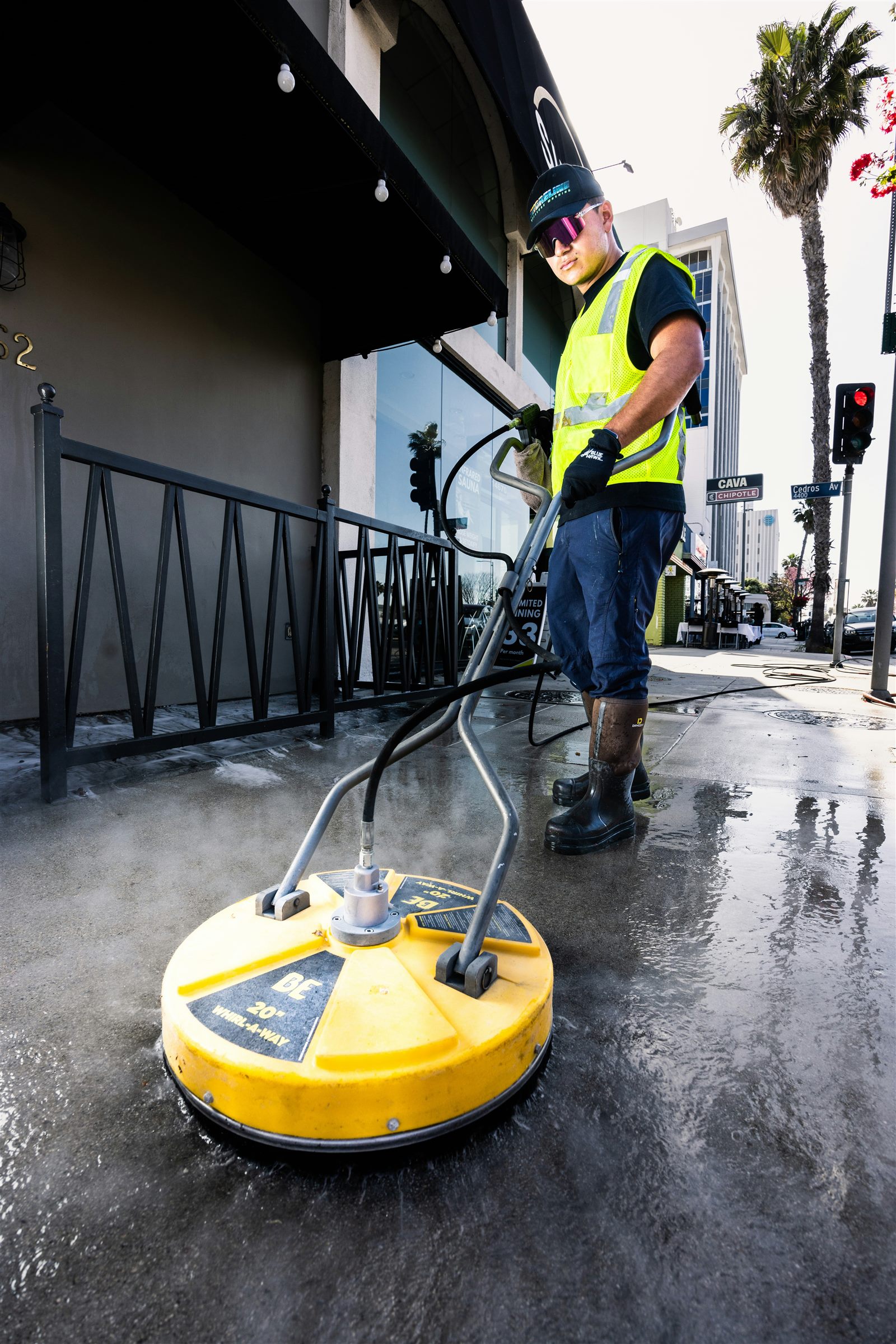 A restoration technician in hi-vis gear cleaning a flooded surface with a pressure washer