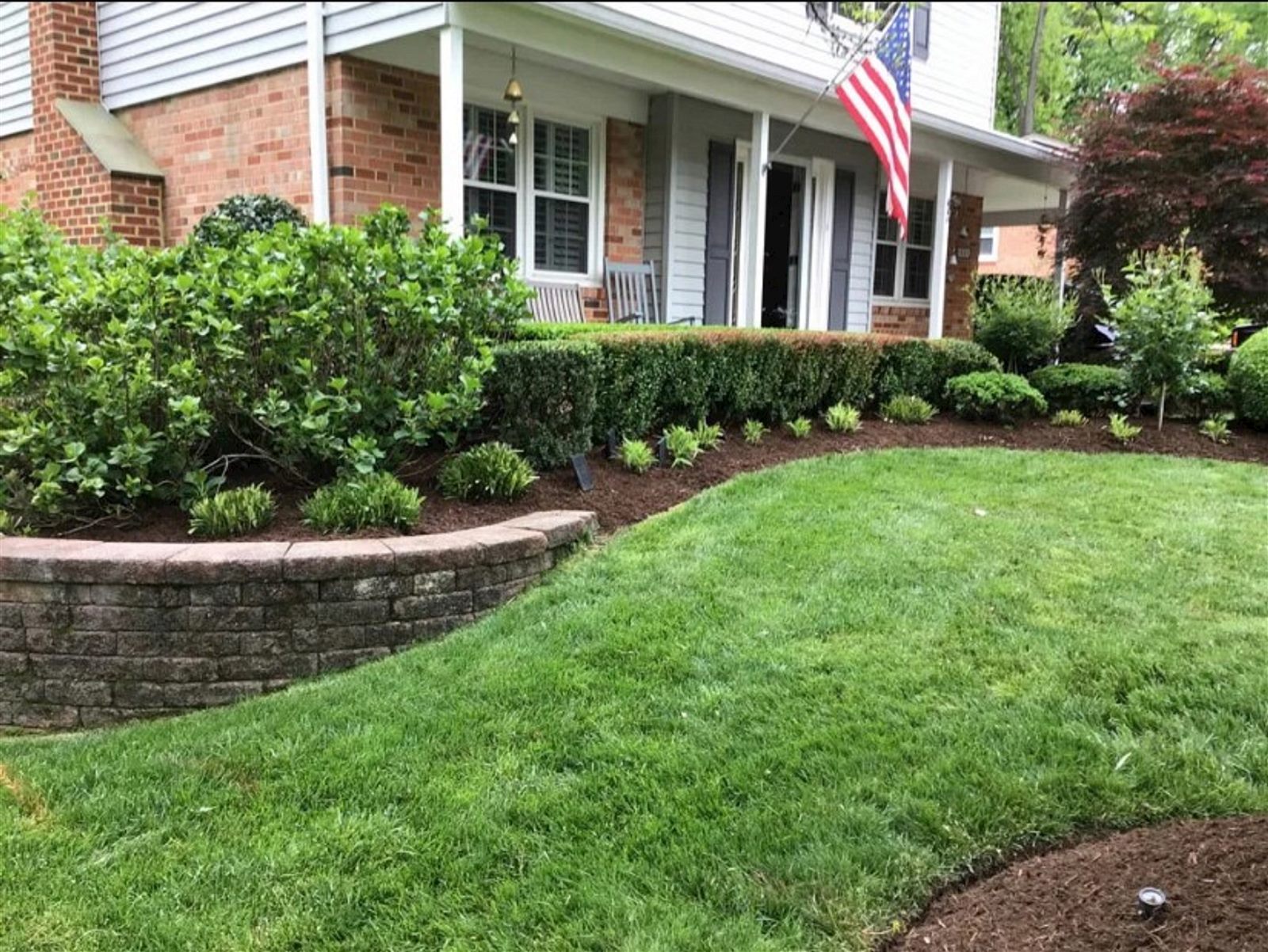 A freshly manicured front yard with trimmed lawn, mulch beds, and shrubs