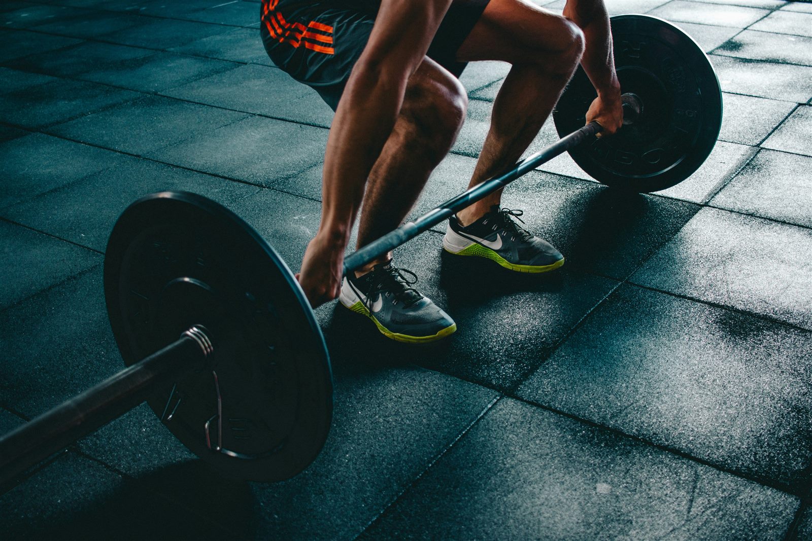 An athlete lifting a loaded barbell from the floor in a strength gym